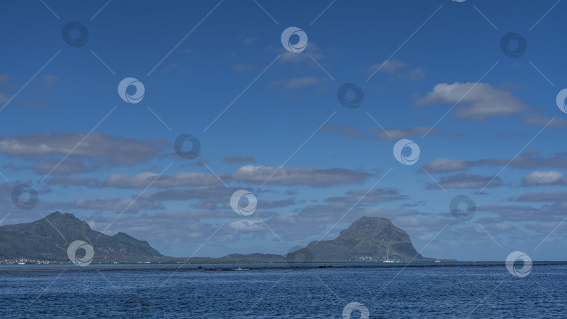 Скачать Тропический остров в океане. Живописные горы на фоне голубого неба, облака. фотосток Ozero