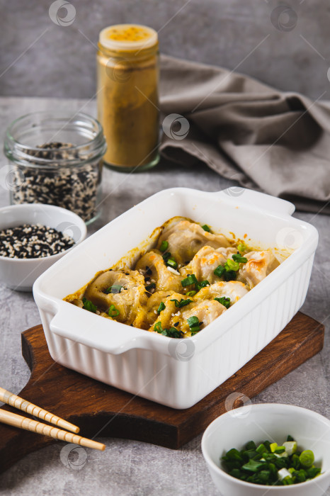 Скачать Вареники, запеченные на одной сковороде с зеленью и соусом, в сковороде на столе, вид сверху фотосток Ozero