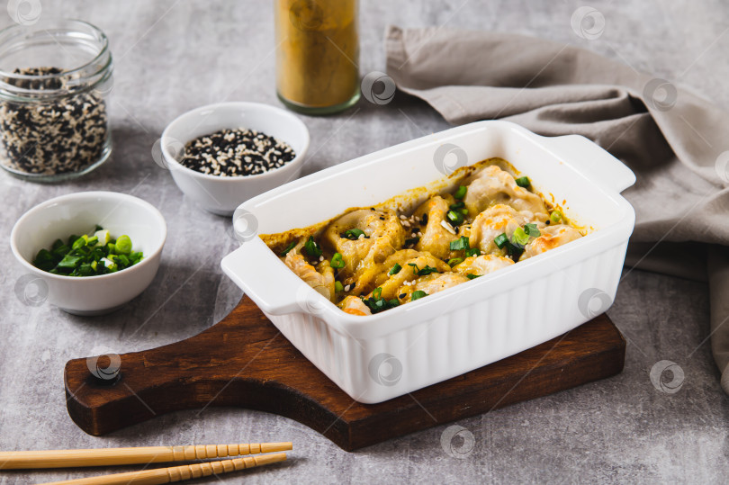 Скачать Вареники, запеченные на одной сковороде с зеленью и соусом, на сковороде на столе фотосток Ozero