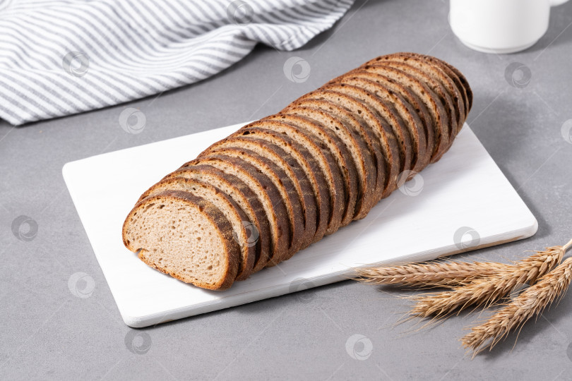 Скачать Нарезанный ломтиками ржаной хлеб выложите на разделочную доску. Ржаной хлеб из цельного зерна фотосток Ozero
