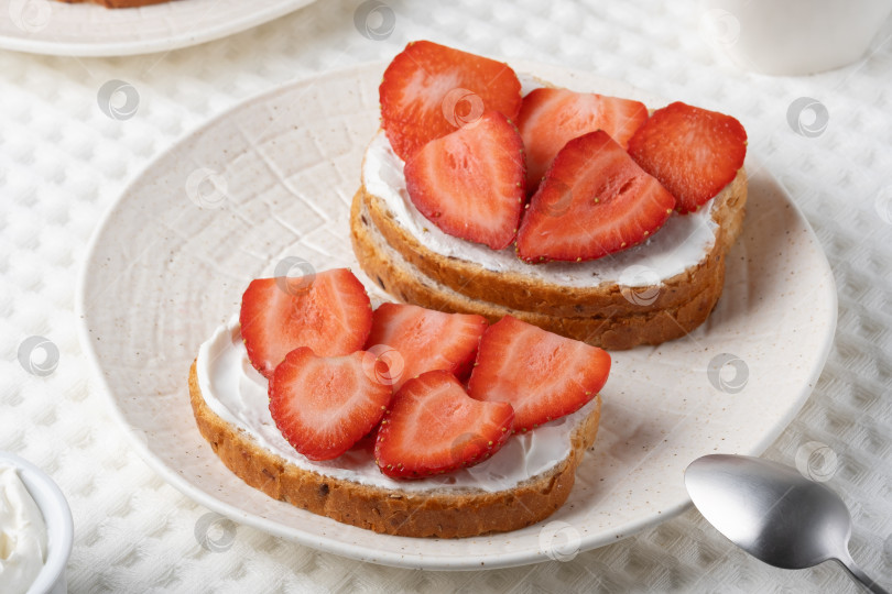 Скачать Вкусный поджаренный хлеб, посыпанный свежей клубникой и сливочным сыром, - отличный вариант для завтрака фотосток Ozero