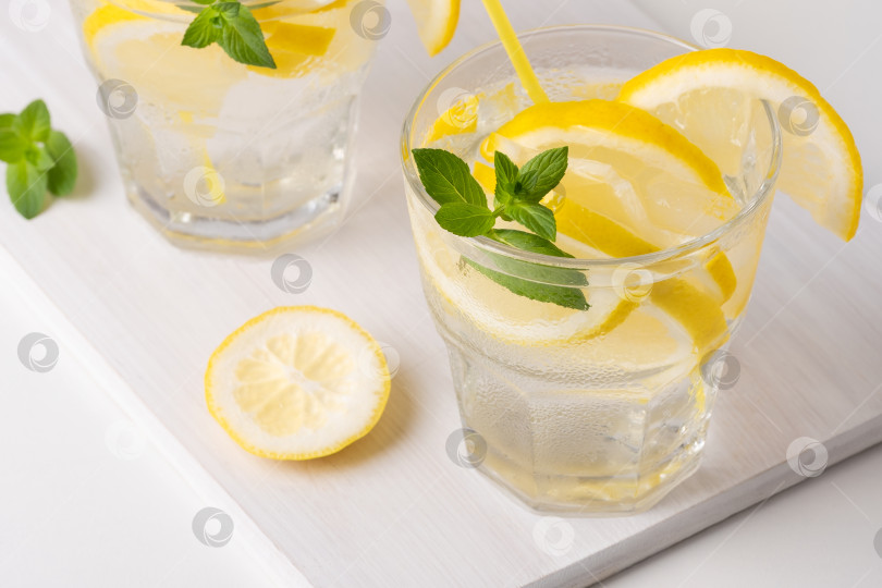 Скачать Освежающие лимонные напитки с мятой подаются солнечным днем на деревянной доске фотосток Ozero