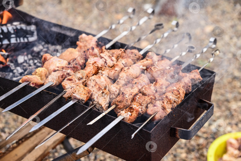 Скачать Шашлык из мяса, приготовленный на углях гриля, с огнем и дымом, поднимающимся на открытом воздухе. Сочные шашлыки-барбекю на шпажках, кулинарный фон для пикника с пространством для копирования. фотосток Ozero