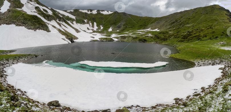 Скачать Снег тает. Горные вершины, зеленая трава и холодное озеро фотосток Ozero