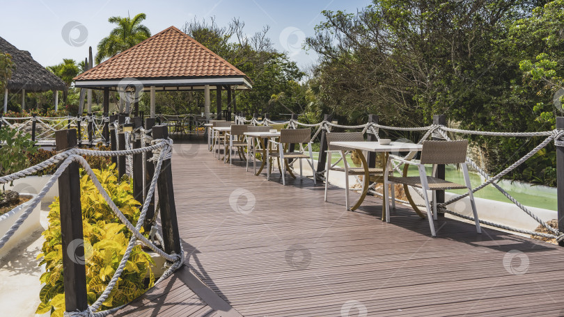 Скачать Кафе на открытом воздухе. Столы и стулья на террасе у веревочных перил. фотосток Ozero