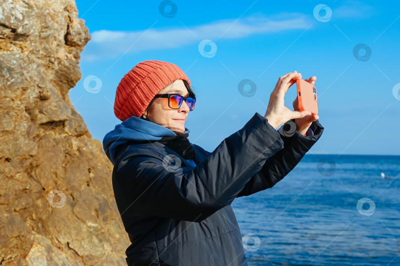 Скачать Россиянка фотографирует побережье Японского моря во Владивостоке холодным солнечным днем. Блогер-путешественник запечатлевает живописный вид на океан и черпает вдохновение. фотосток Ozero