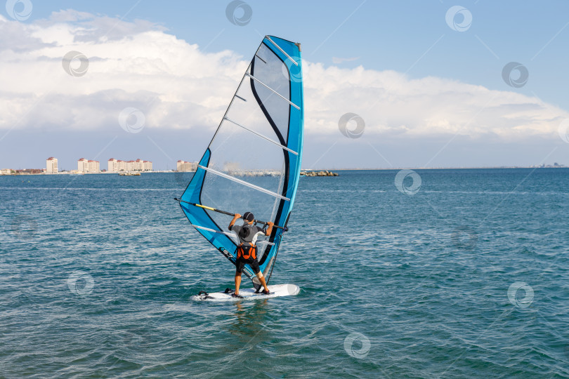 Скачать Евпатория, Россия - сентября 16, 2025- Мужчина, занимающийся виндсерфингом фотосток Ozero