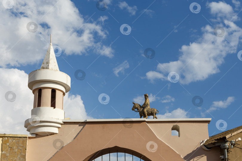 Скачать Евпатория, Россия - сентября 16, 2025- Фигурка мужчины на ослике над Одун базар-капусы (Дровяные ворота) фотосток Ozero