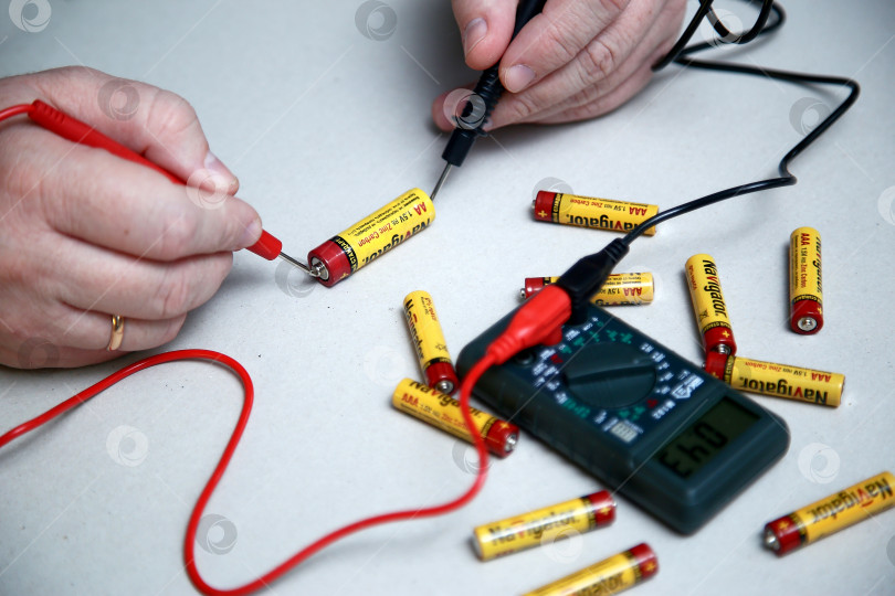 Скачать Краснодар, Россия - 18 ноября 2018 г. Проверка заряда аккумулятора с помощью мультиметра крупным планом. фотосток Ozero