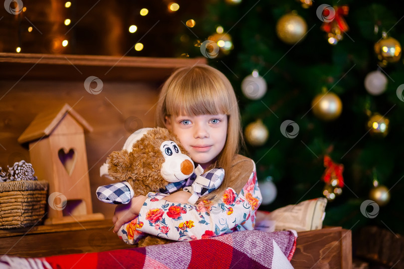 Скачать Маленькая девочка держит игрушку возле рождественской елки фотосток Ozero