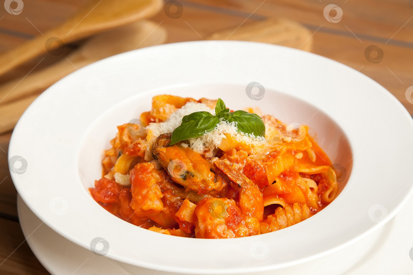 Скачать Паста с морепродуктами в томатном соусе на белом блюде. Европейская кухня. фотосток Ozero