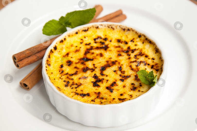 Скачать Десерт крем-брюле с палочками корицы на белом блюде фотосток Ozero