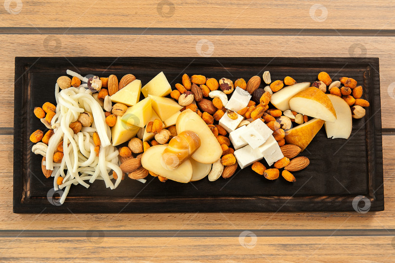 Скачать Ассорти из орехов и сыра на деревянной доске фотосток Ozero