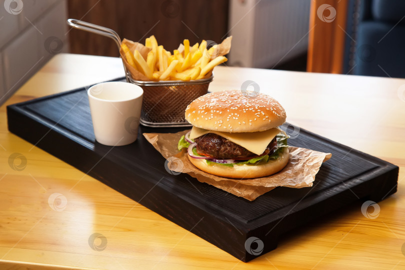 Скачать Гамбургер и картофель фри на деревянной доске для сервировки блюд. фотосток Ozero