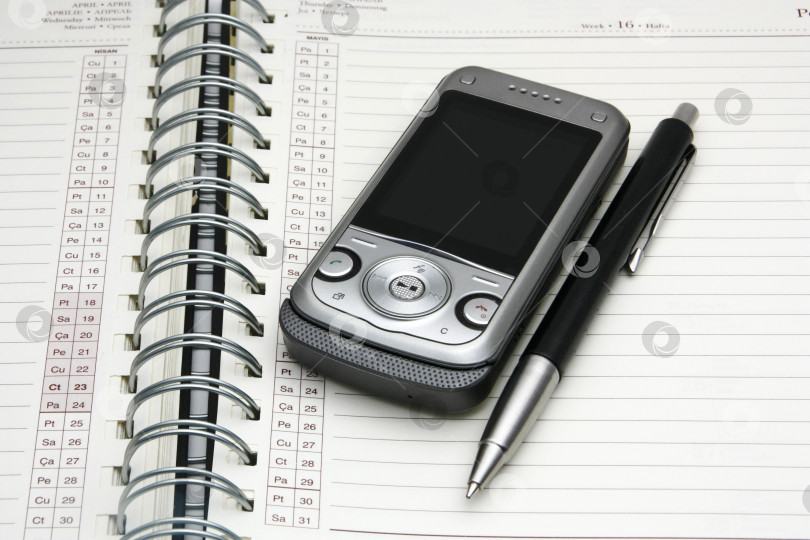 Скачать Телефон-ежедневник и ручка крупным планом. Расписание деловых встреч и важные концептуальные заметки. График. фотосток Ozero