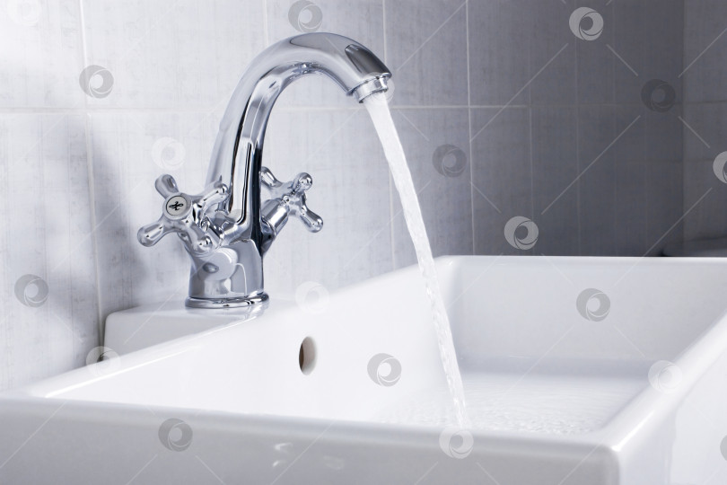 Скачать Новая сантехника. Хромированный смеситель и белая раковина в ванной комнате. фотосток Ozero