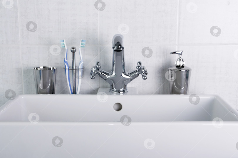 Скачать Новая сантехника. Хромированный смеситель и белая раковина в ванной комнате. фотосток Ozero