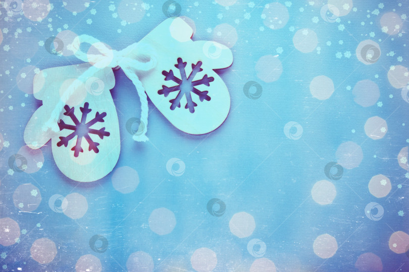 Скачать Деревянная игрушечная варежка. Праздничный фон с яркими рождественскими и новогодними огоньками из гирлянды. Винтажная тонировка и царапины. фотосток Ozero