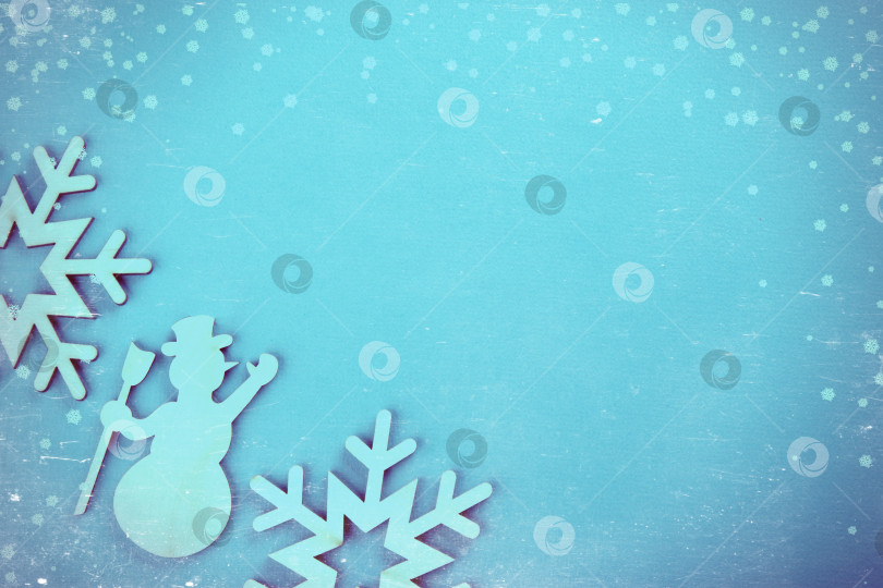 Скачать Деревянный игрушечный снеговик на голубом новогоднем фоне. Винтажная тонировка и царапины. фотосток Ozero