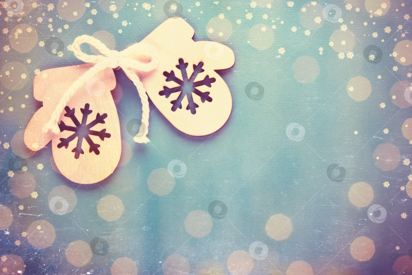 Скачать Деревянная игрушечная варежка. Праздничный фон с яркими рождественскими и новогодними огоньками из гирлянды. Винтажная тонировка и царапины. фотосток Ozero