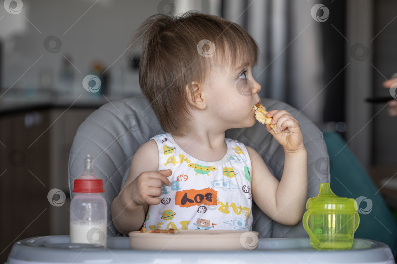 Скачать Маленькая девочка вкусно ест, сидя за детским столиком фотосток Ozero