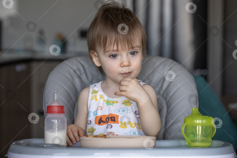 Скачать Маленькая девочка вкусно ест, сидя за детским столиком фотосток Ozero