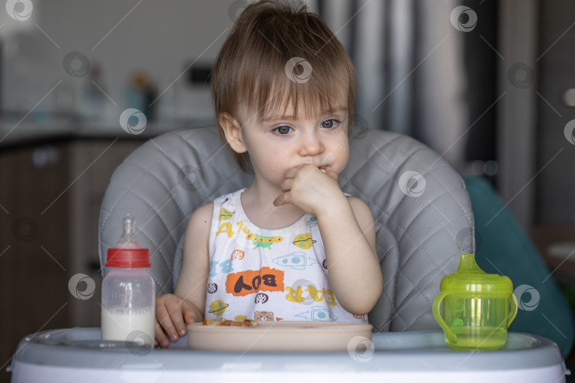 Скачать Маленькая девочка вкусно ест, сидя за детским столиком фотосток Ozero