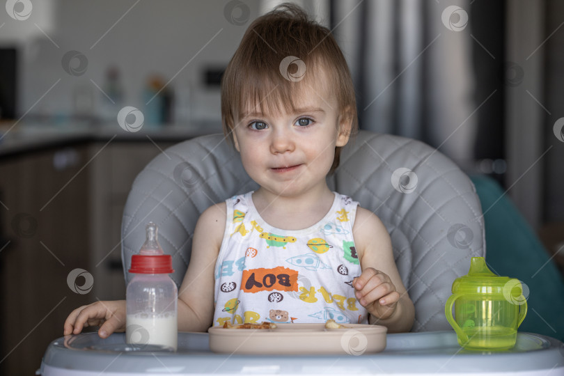 Скачать Маленькая девочка вкусно ест, сидя за детским столиком фотосток Ozero