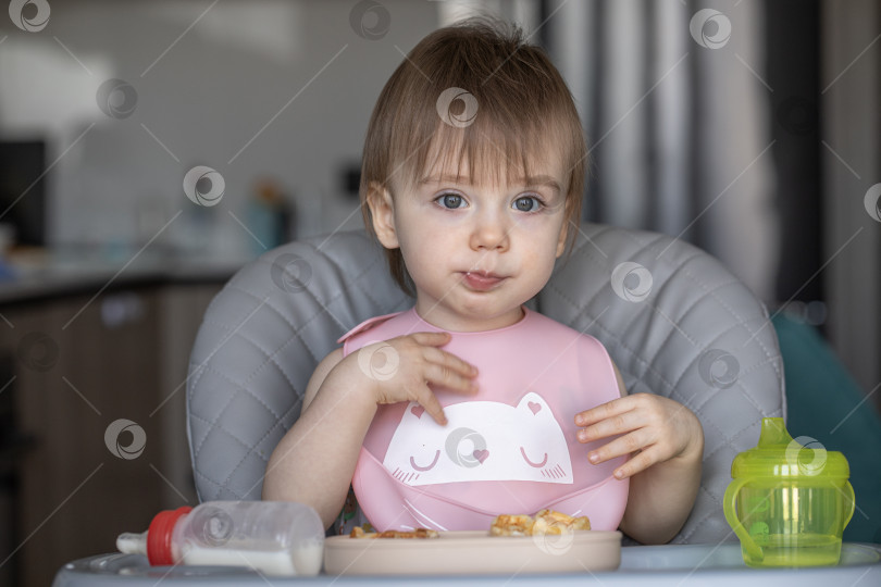 Скачать Маленькая девочка вкусно ест, сидя за детским столиком фотосток Ozero