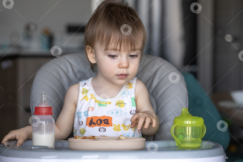 Скачать Маленькая девочка вкусно ест, сидя за детским столиком фотосток Ozero