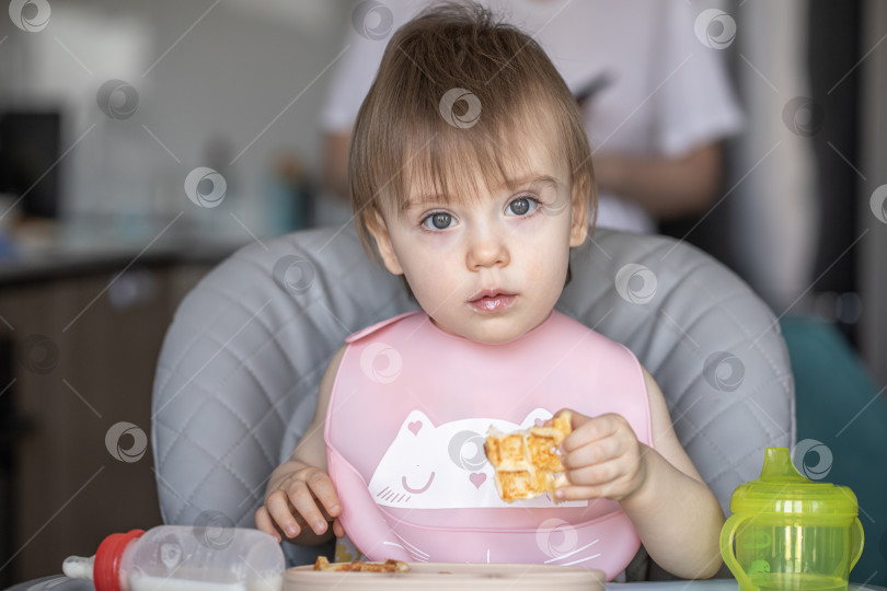 Скачать Маленькая девочка вкусно ест, сидя за детским столиком фотосток Ozero