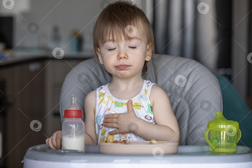 Скачать Маленькая девочка вкусно ест, сидя за детским столиком фотосток Ozero