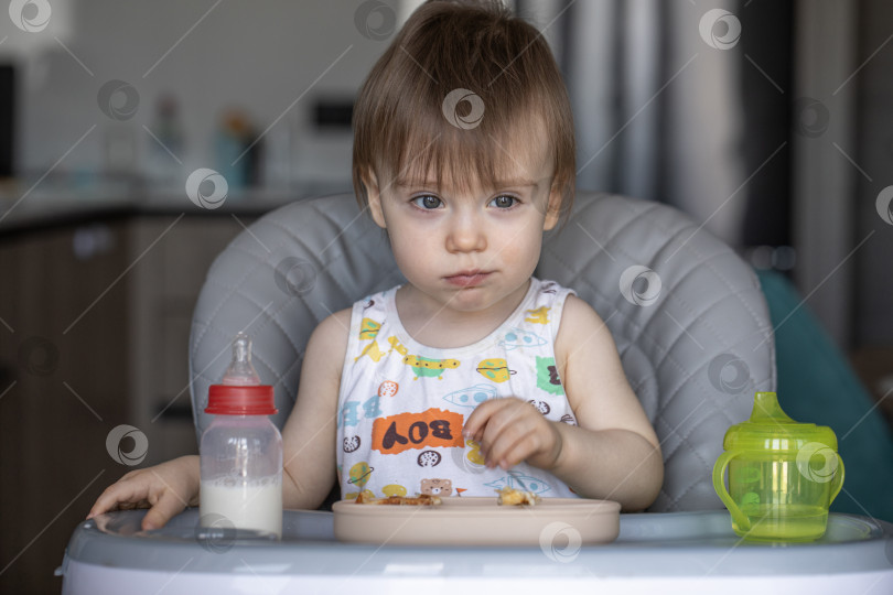 Скачать Маленькая девочка вкусно ест, сидя за детским столиком фотосток Ozero