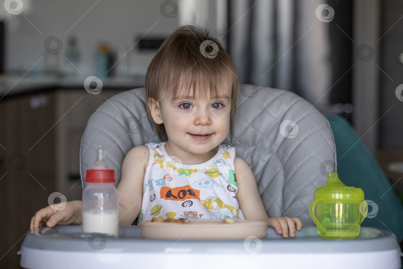 Скачать Маленькая девочка вкусно ест, сидя за детским столиком фотосток Ozero