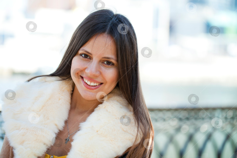 Скачать Счастливая молодая девушка в дубленке на фоне города фотосток Ozero