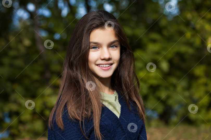 Скачать Симпатичная маленькая девочка-брюнетка позирует на фоне осеннего парка фотосток Ozero