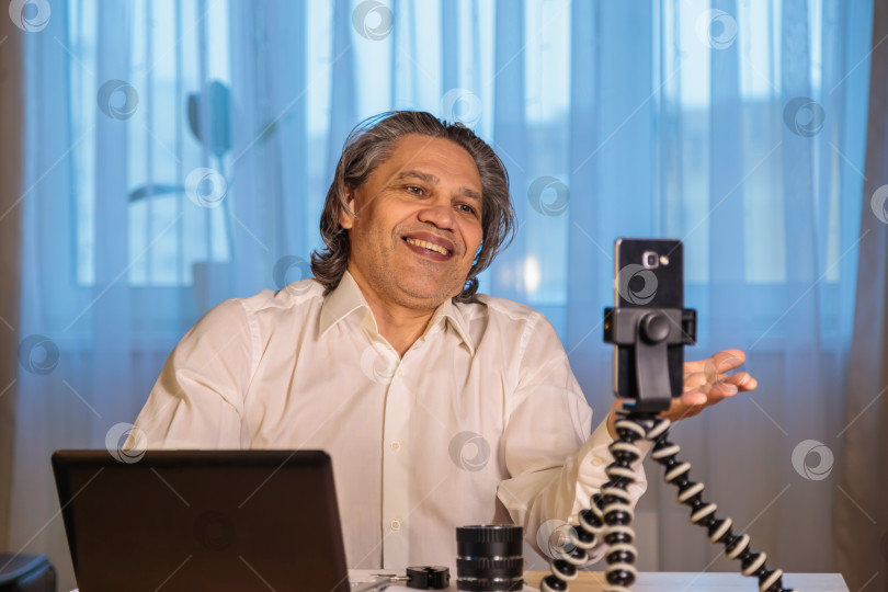 Скачать 50-летний блогер записывает видео для блога на свой смартфон. фотосток Ozero