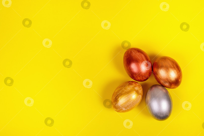 Скачать Разноцветные яйца на однородном желтом фоне с местом для текста. фотосток Ozero