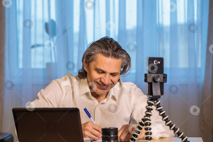 Скачать 50-летний блогер записывает видео для блога на свой смартфон. фотосток Ozero