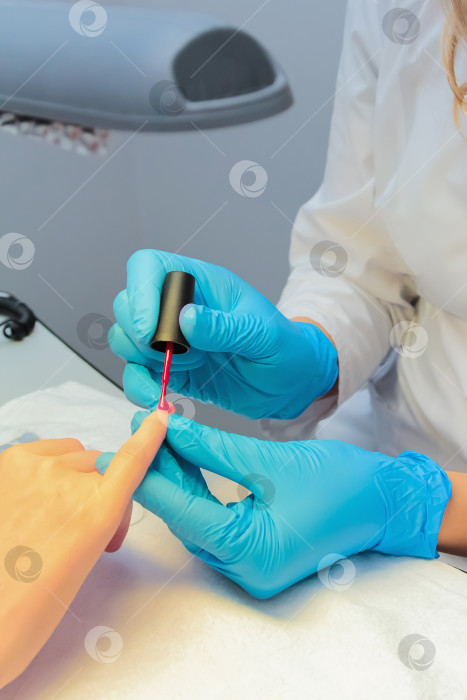 Скачать В салоне красоты женщине делают маникюр, покрывают ноготь лаком. фотосток Ozero