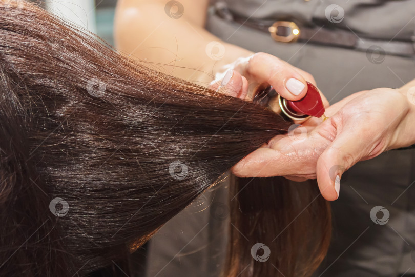 Скачать Парикмахер ухаживает за волосами, нанося питательное средство фотосток Ozero
