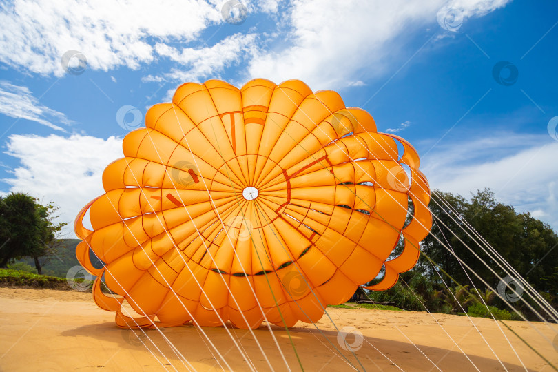 Скачать Для туристов на ветру раскрывается ярко-оранжевый парашют. фотосток Ozero