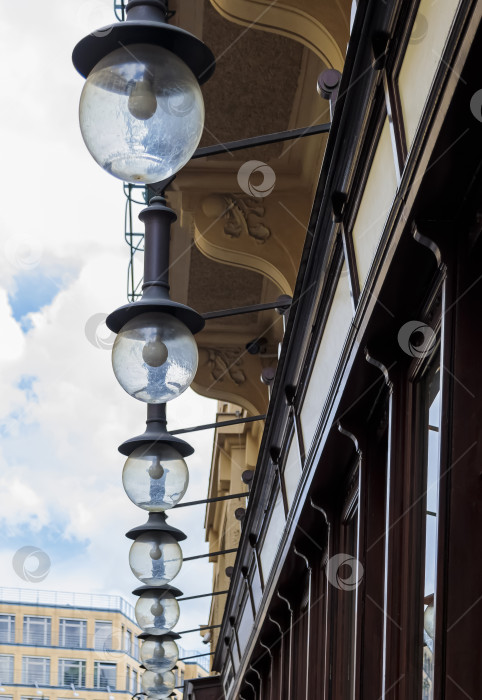 Скачать На фасаде здания рядом с тротуаром висят круглые стеклянные фонари. фотосток Ozero