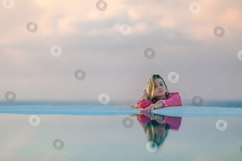Скачать Молодая девушка на рассвете у морского бассейна, спокойная и расслабленная фотосток Ozero