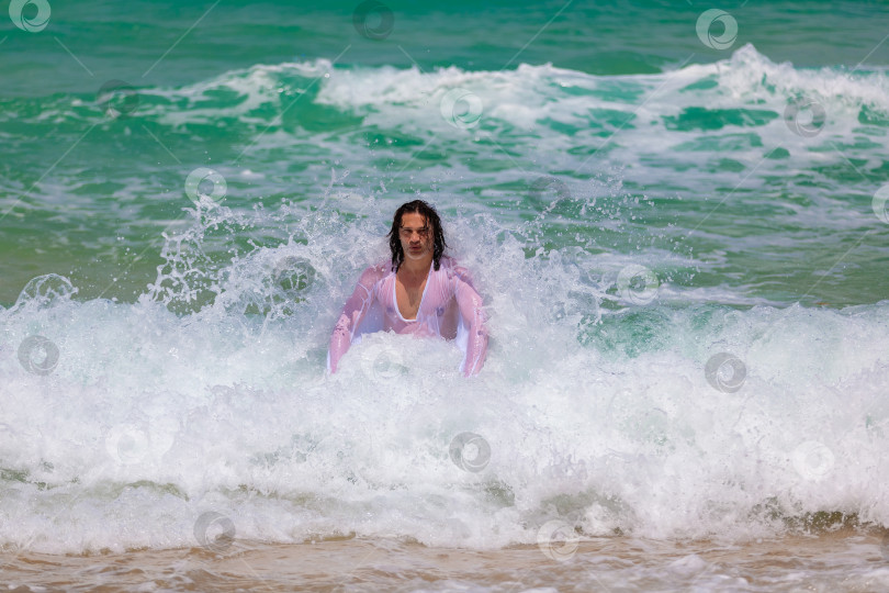 Скачать Мужчина с длинными волосами сопротивляется мощным волнам фотосток Ozero
