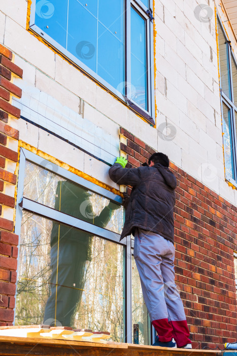 Скачать Мужчина работает дрелью, крепит термопанели из клинкера фотосток Ozero