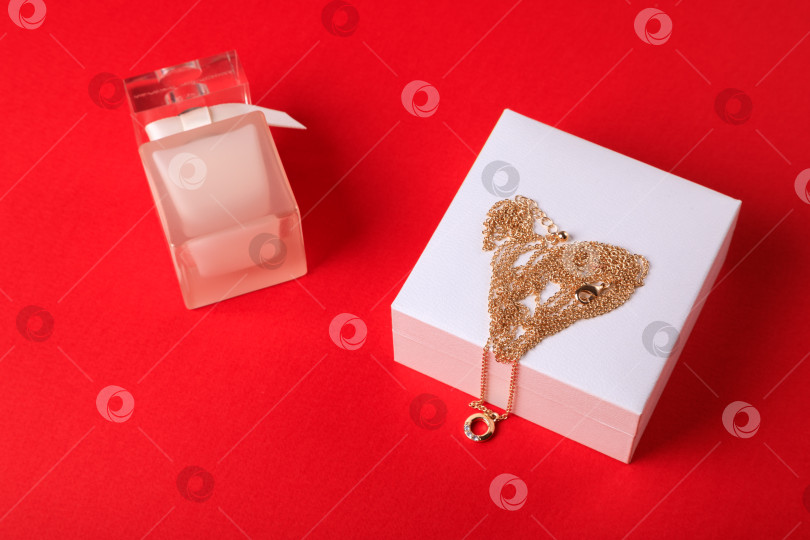 Скачать день святого Валентина. Духи и коробочка с цепочкой на красном фоне.. фотосток Ozero