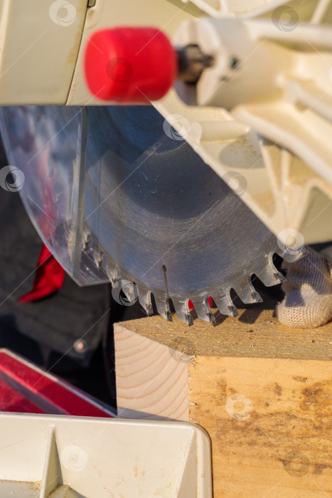 Скачать Рабочий-мужчина распиливает брусок электрической пилой с диском. фотосток Ozero