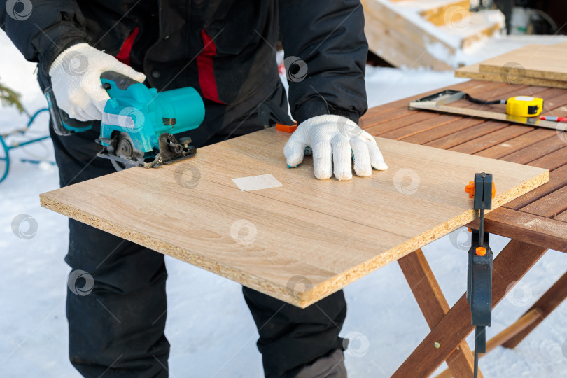 Скачать Рабочий распиливает деревянную панель циркулярной пилой. фотосток Ozero