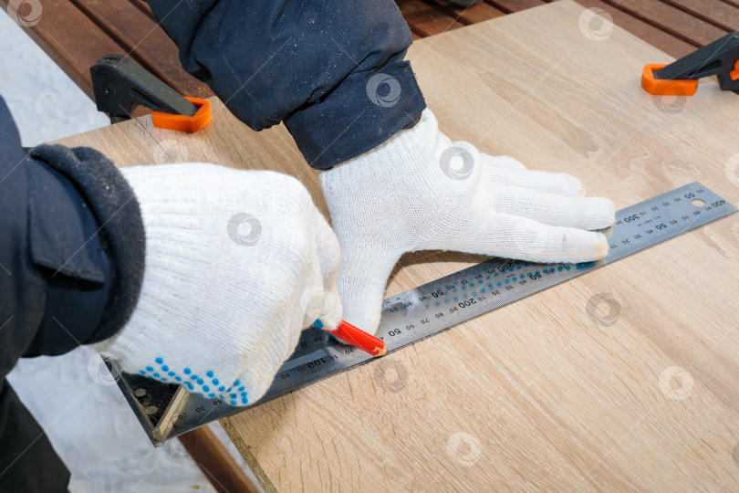 Скачать Мужчина, рабочий рисует карандашом на доске из ДСП. фотосток Ozero